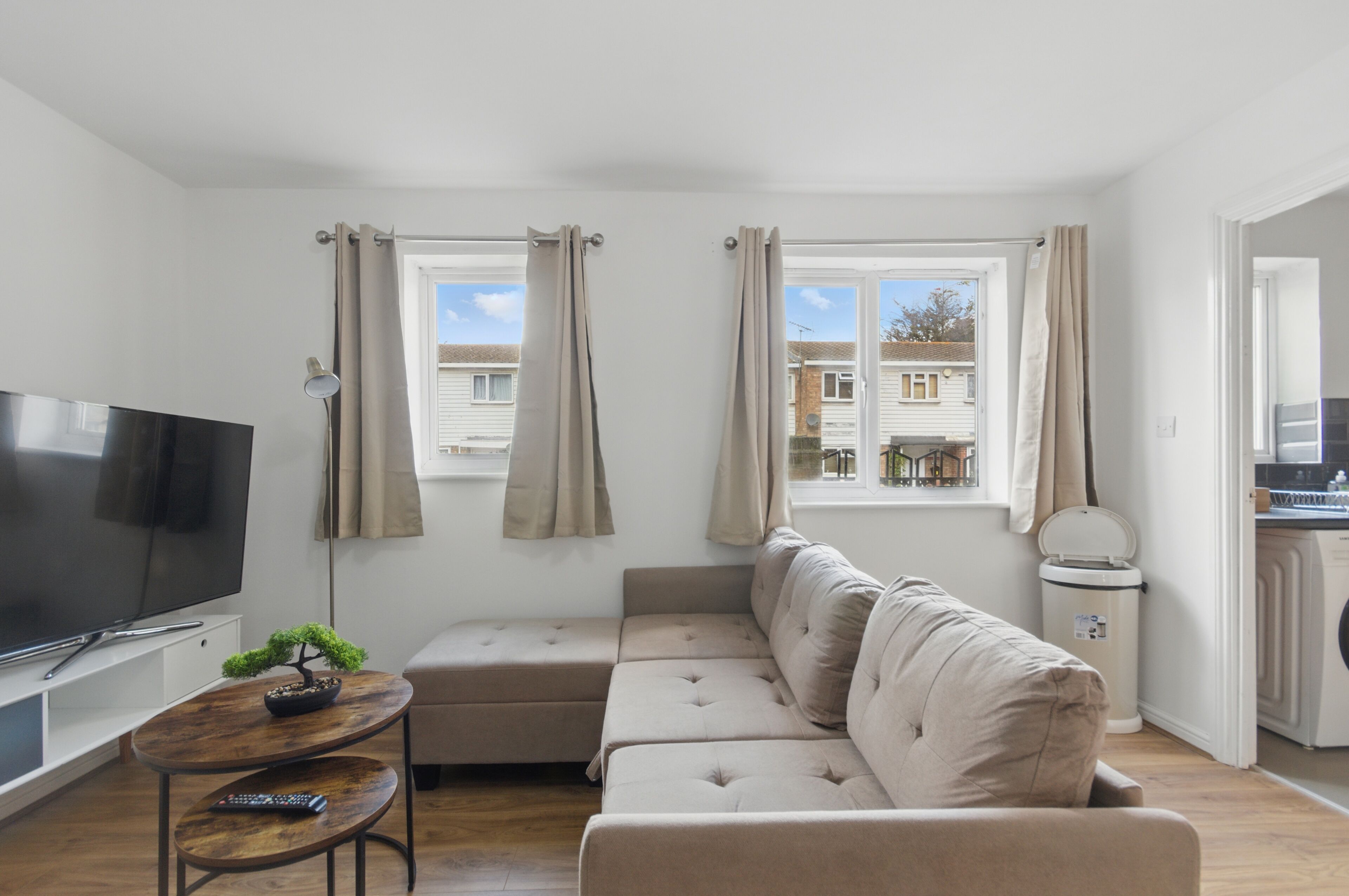 A living room with a TV, sofa, and windows.