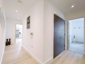 A modern interior with a kitchen, a dark door, and a hallway leading to another room. - Modern 2-Bed Apartment In Poplar Near Canary Wharf (London)