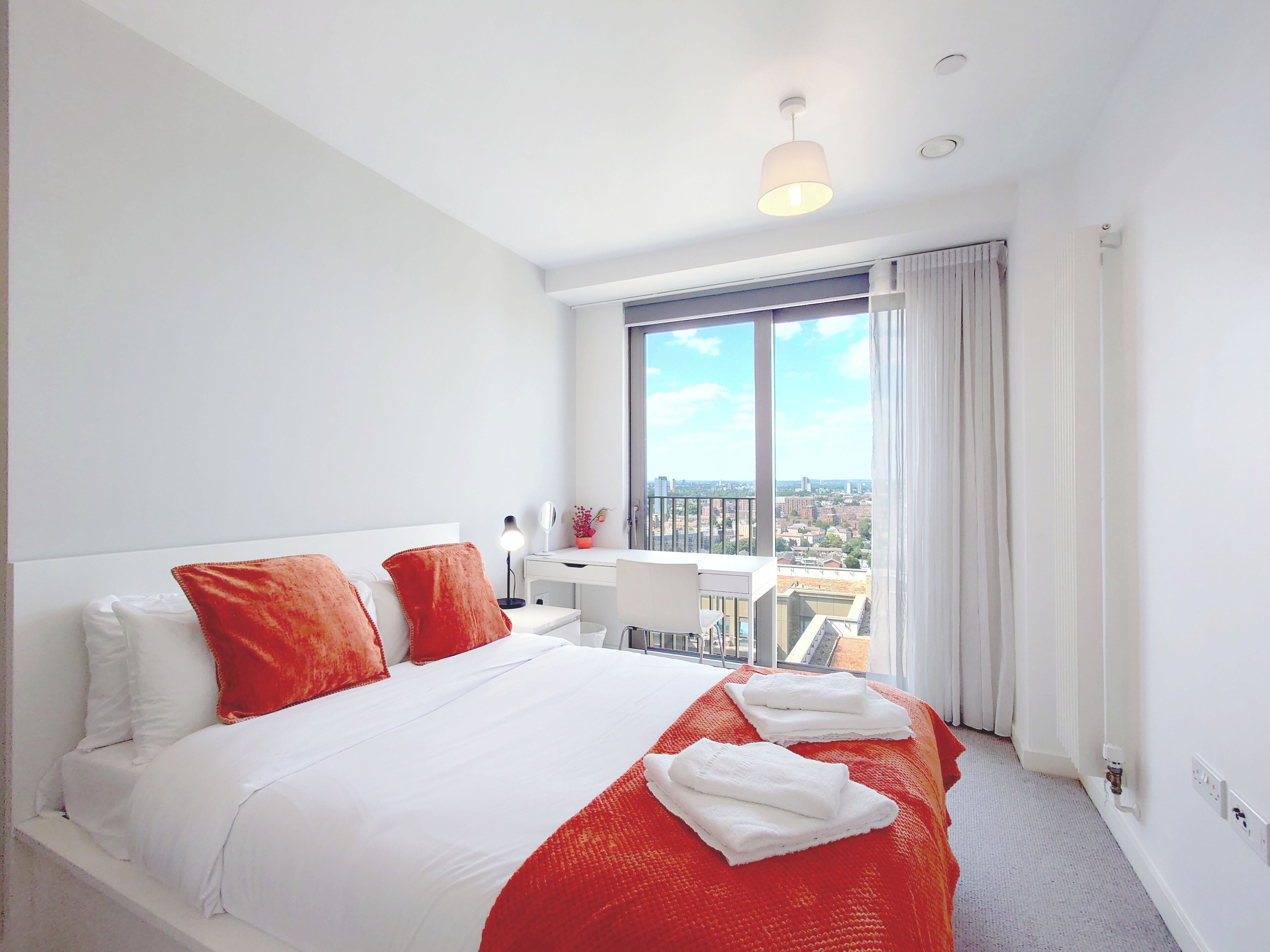 A hotel room with a large bed, a desk, and a view of the city.