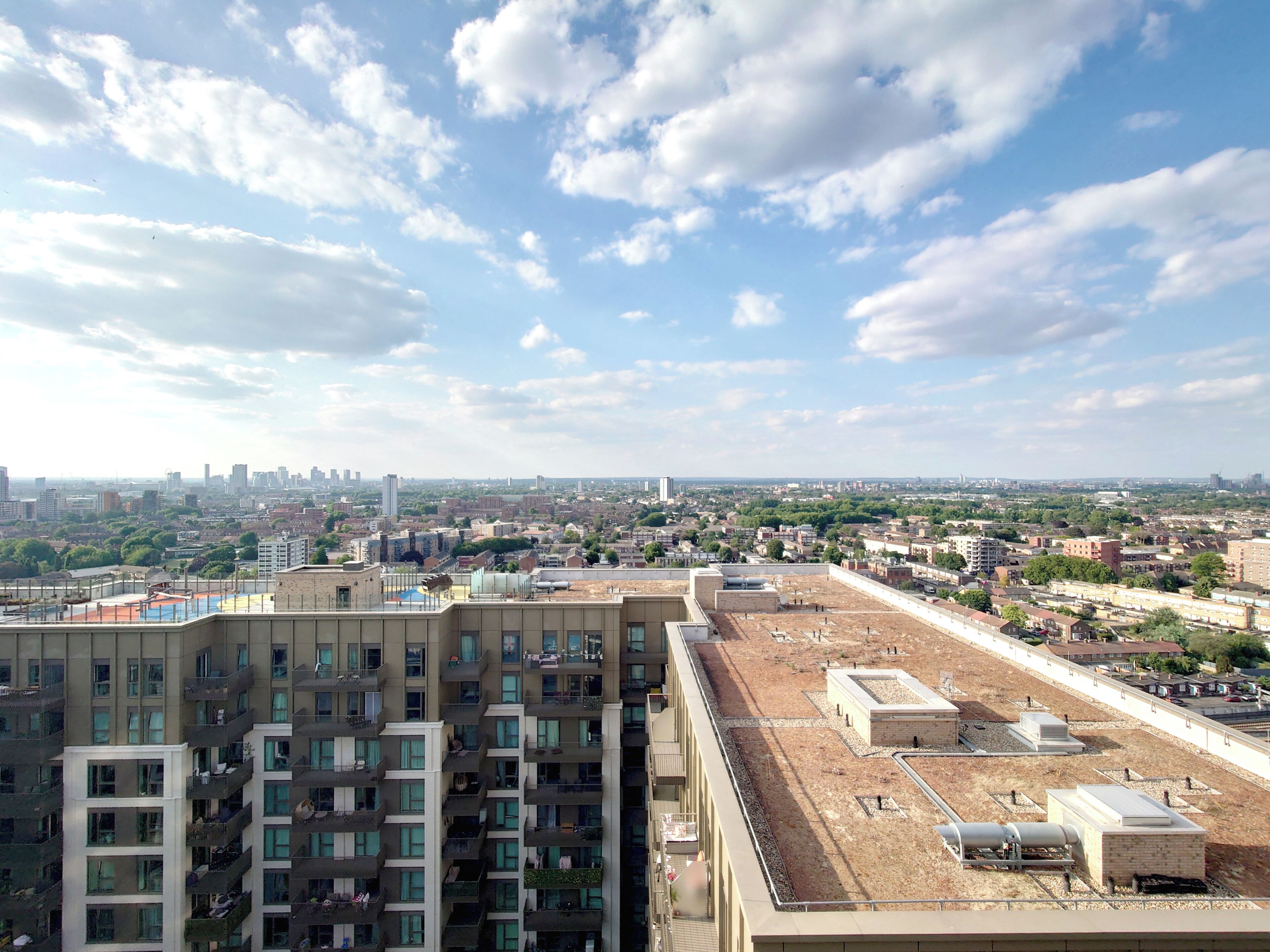 Un edificio alto con diversi piani, una terrazza sul tetto e un panorama urbano sullo sfondo.