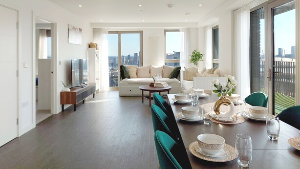 A modern living room with a dining area, large windows, and a city view. - Capital Stay - Three Bed Apartment In Excel (London)