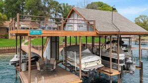 Ein schwimmendes Haus mit Terrasse, überdachtem Bereich und Bootsanleger.