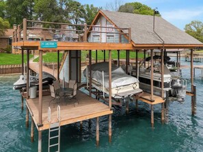 A floating house with a deck, a covered area, and a boat dock. - Cedar Creek Lake Escape • Lakefront + Private Dock (Mabank)