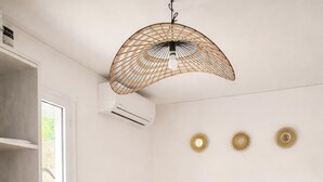 Une chambre à coucher avec un lit, un luminaire suspendu et un climatiseur fixé au mur.