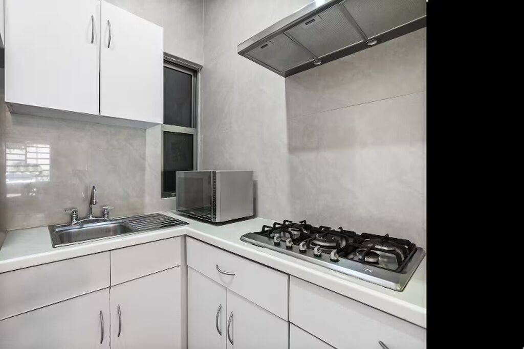A kitchen with white cabinets, a stainless steel sink, a microwave, and a gas stove.