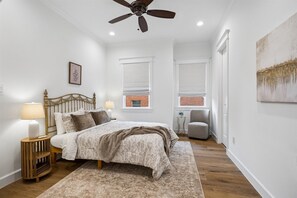 A bedroom with a bed, a nightstand, a lamp, a ceiling fan, and a window with a view of a brick building. - Elegant Home With Elevator @Med Center, MDAnderson, NRG, Rice University (Houston)