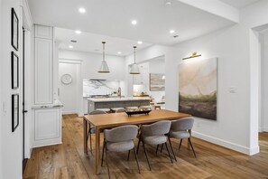 A modern kitchen with white cabinetry, a wooden dining table, and gray chairs. - Elegant Home With Elevator @Med Center, MDAnderson, NRG, Rice University (Houston)