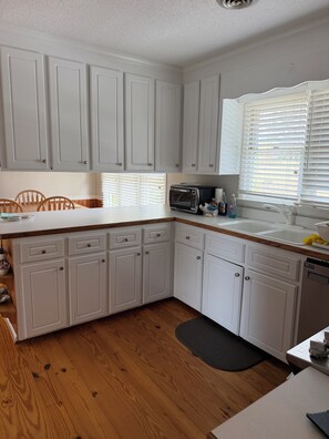 A kitchen with white cabinets, a microwave, and a sink. - Spacious 4-bedroom lake house in delightful Manson with AC/ rec room/ dock (Manson)