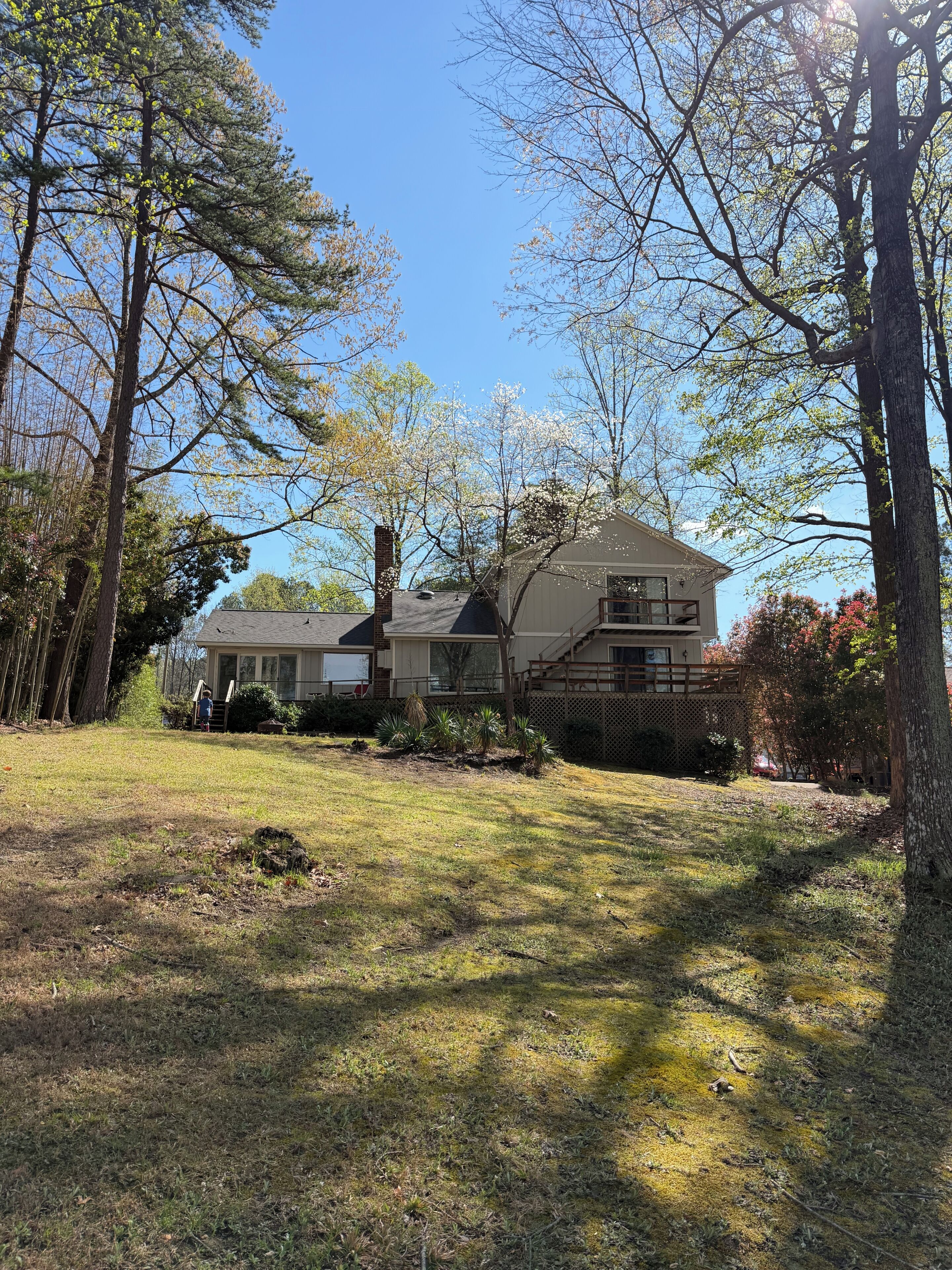 A two-story house with a large front yard, surrounded by trees and a fence.