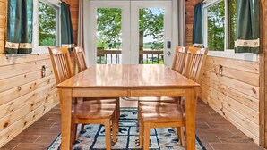 Un interior de madera con una mesa de comedor, sillas, un tapete estampado y una araña.