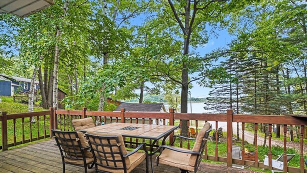 Una terraza de madera con una mesa y sillas, con vistas a un lago.