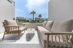 Un balcon avec un canapé, deux fauteuils et une petite table.