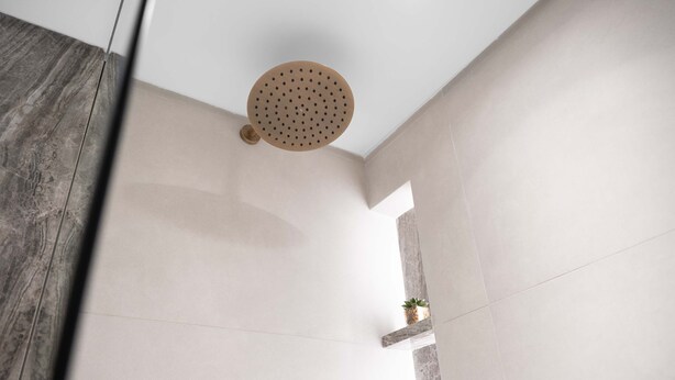 A modern shower with a circular head, a small plant on a shelf, and a marble floor. - Free Housekeeping Visits During Your Stay - Stayshort - Comfortable Studio Stay in Arjan Sleeps 2 With Balcony (Dubai)
