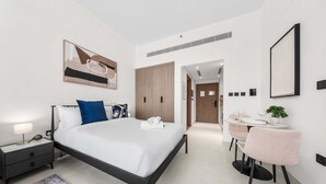 A modern hotel room with a bed, bedside table, lamp, and a small desk with a chair. - Free Housekeeping Visits During Your Stay - Stayshort - Comfortable Studio Stay in Arjan Sleeps 2 With Balcony (Dubai)