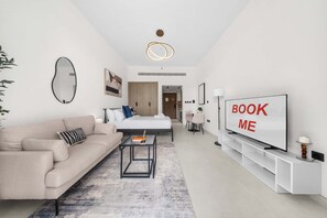 Un salon moderne avec un canapé, une table basse, un téléviseur et un panneau indiquant « RÉSERVEZ-MOI ».