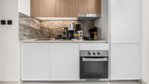 A modern kitchen with white cabinetry, a stainless steel range, and a built-in oven. - Free Housekeeping Visits During Your Stay - Stayshort - Comfortable Studio Stay in Arjan Sleeps 2 With Balcony (Dubai)