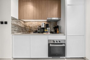 A modern kitchen with white cabinetry, a stainless steel range, and a built-in oven. - Free Housekeeping Visits During Your Stay - Stayshort - Comfortable Studio Stay in Arjan Sleeps 2 With Balcony (Dubai)