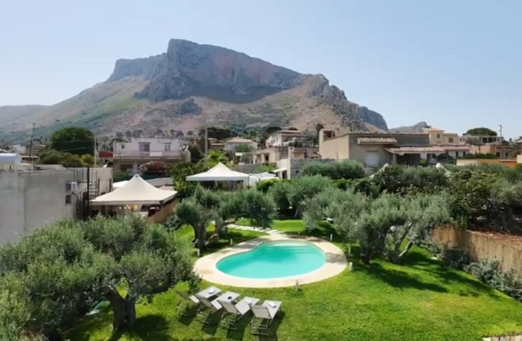 A residential area with a swimming pool surrounded by greenery and a mountain in the background.