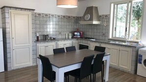 A kitchen with a dining table, chairs, a stove, a microwave, and a window. - Villa with Private Pool, Sea View in Sicily, Palermo-Terrasini. Family friendly (Serra)