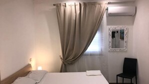 A hotel room with a bed, a chair, a window with curtains, and an air conditioning unit. - Villa with Private Pool, Sea View in Sicily, Palermo-Terrasini. Family friendly (Serra)