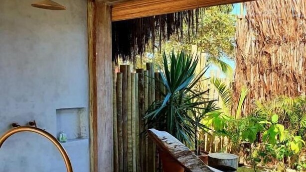 A spa area with a stone bench, a wooden table with towels, and a thatched-roof entrance. - Villa Fulô Casa Hotel (Porto Seguro)
