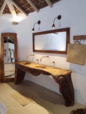 A rustic bathroom with a wooden vanity, a large mirror, and a hanging towel rack. - Villa Fulô Casa Hotel (Porto Seguro)