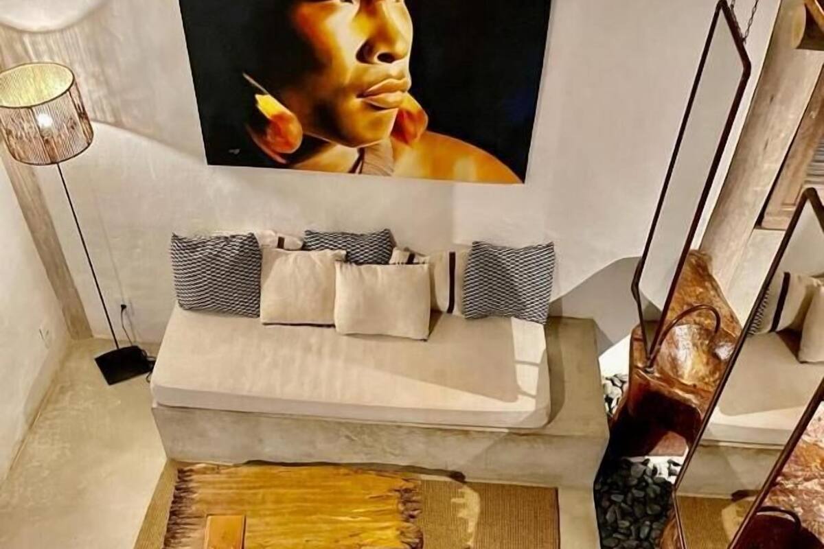 Una sala de estar moderna con sofá, cojines decorativos, una mesa de centro de madera y un televisor montado en la pared.