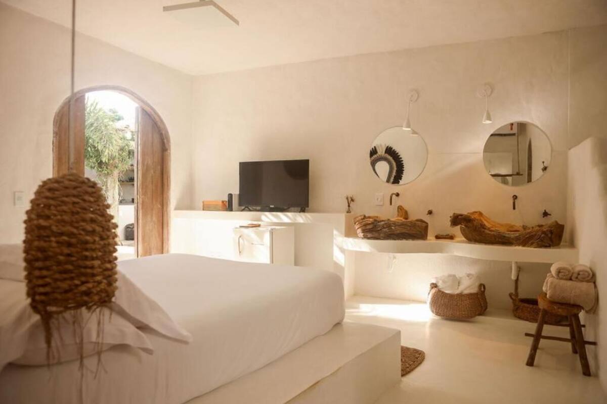 Un dormitorio con cama, televisor, un espejo grande y un estante de madera con toallas.
