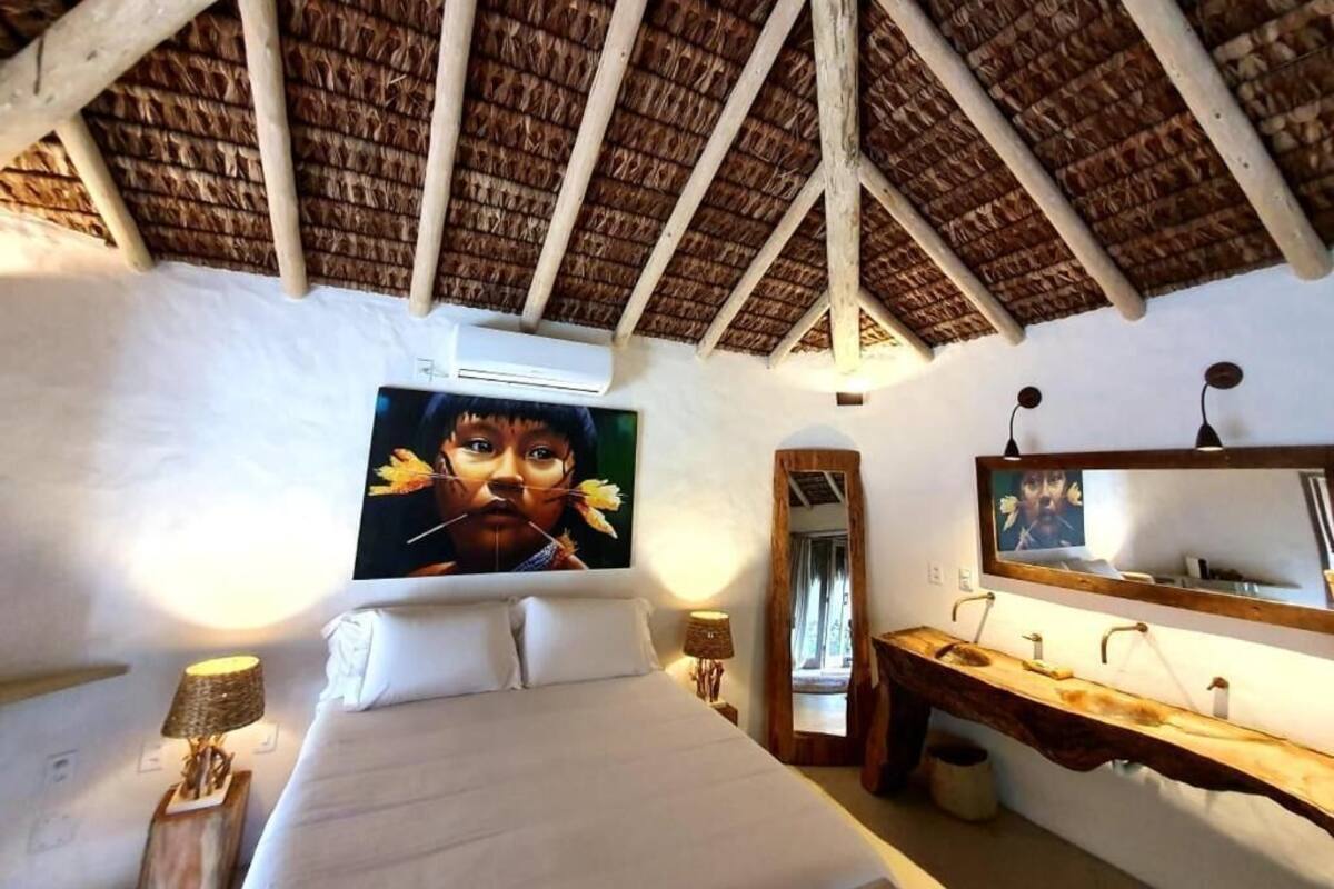Un dormitorio con una cama, un tocador de madera, un espejo grande y un techo con vigas de madera.