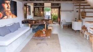A spacious living area with a high ceiling, a sofa set, a coffee table, and a dining table. - Villa Fulô Casa Hotel (Porto Seguro)