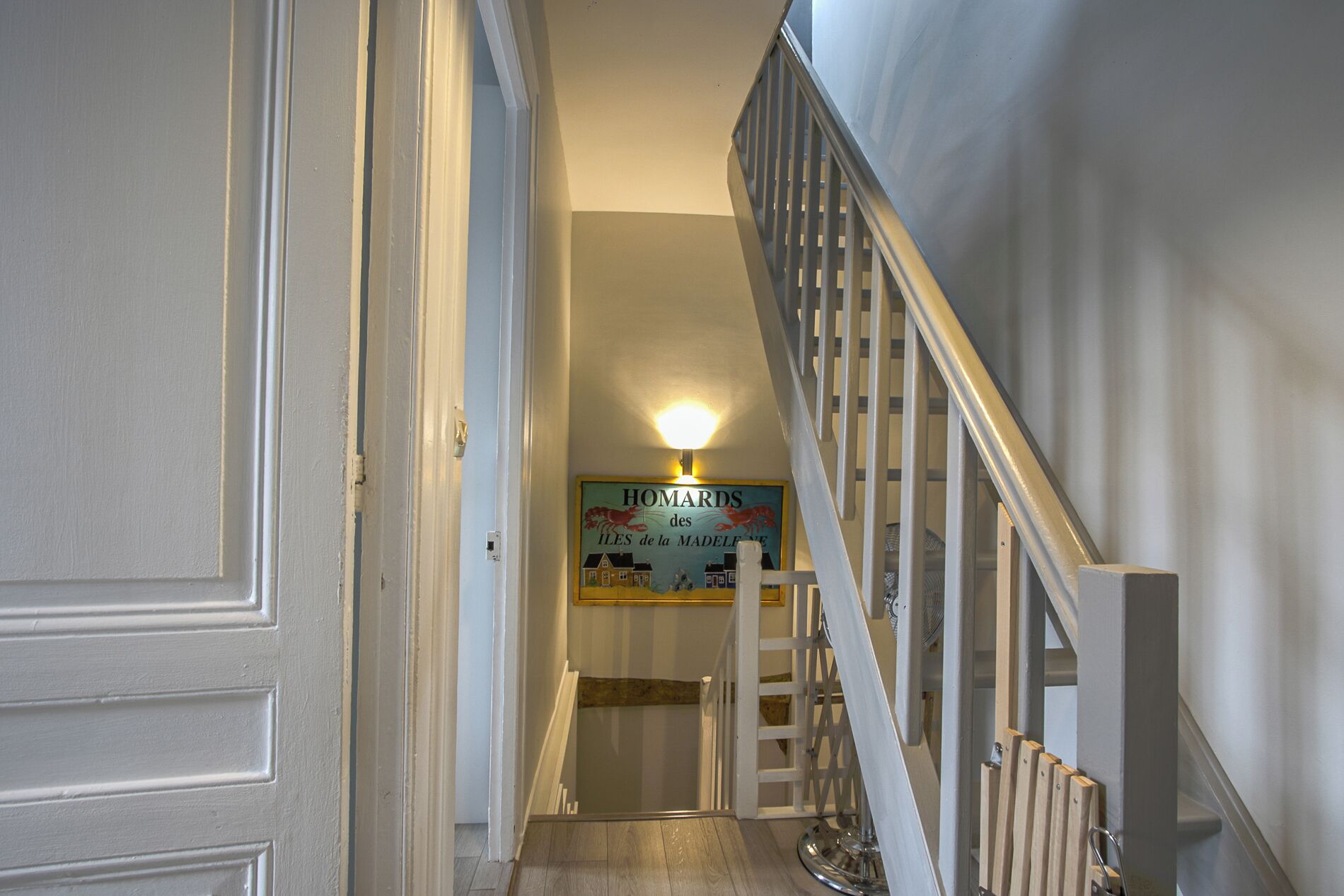 A staircase with a wooden handrail and a light fixture above it.