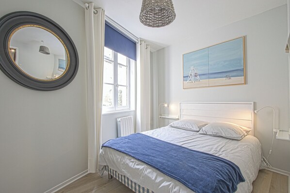 A bedroom with a bed, a window, a mirror, a painting, and a radiator. - La Venelle des Greniers à Sel (Honfleur)
