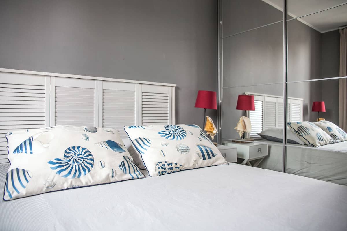 Une chambre d’hôtel avec un lit, deux tables de chevet, un miroir et des lampes rouges.