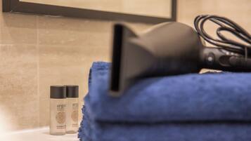 A bathroom with a towel, a hairdryer, and two bottles of shampoo.