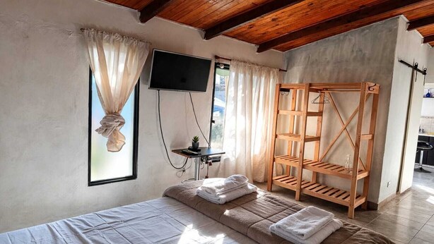 Ein Schlafzimmer mit einem Bett, einem Fernseher, einer Holzregal und einem Fenster mit Vorhängen.