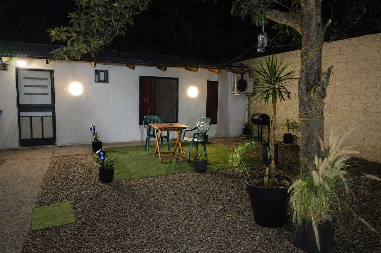 Un pequeño edificio con patio, mesa, sillas y plantas en macetas.