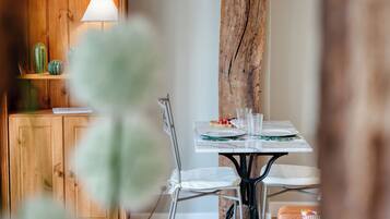 A dining area with a wooden cabinet, a lamp, a cactus, and a table set for two.