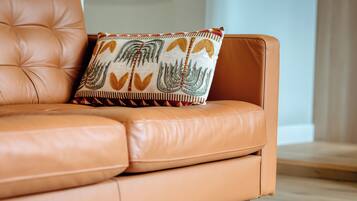 Un canapé en cuir couleur fauve agrémenté d’un coussin décoratif à motifs.