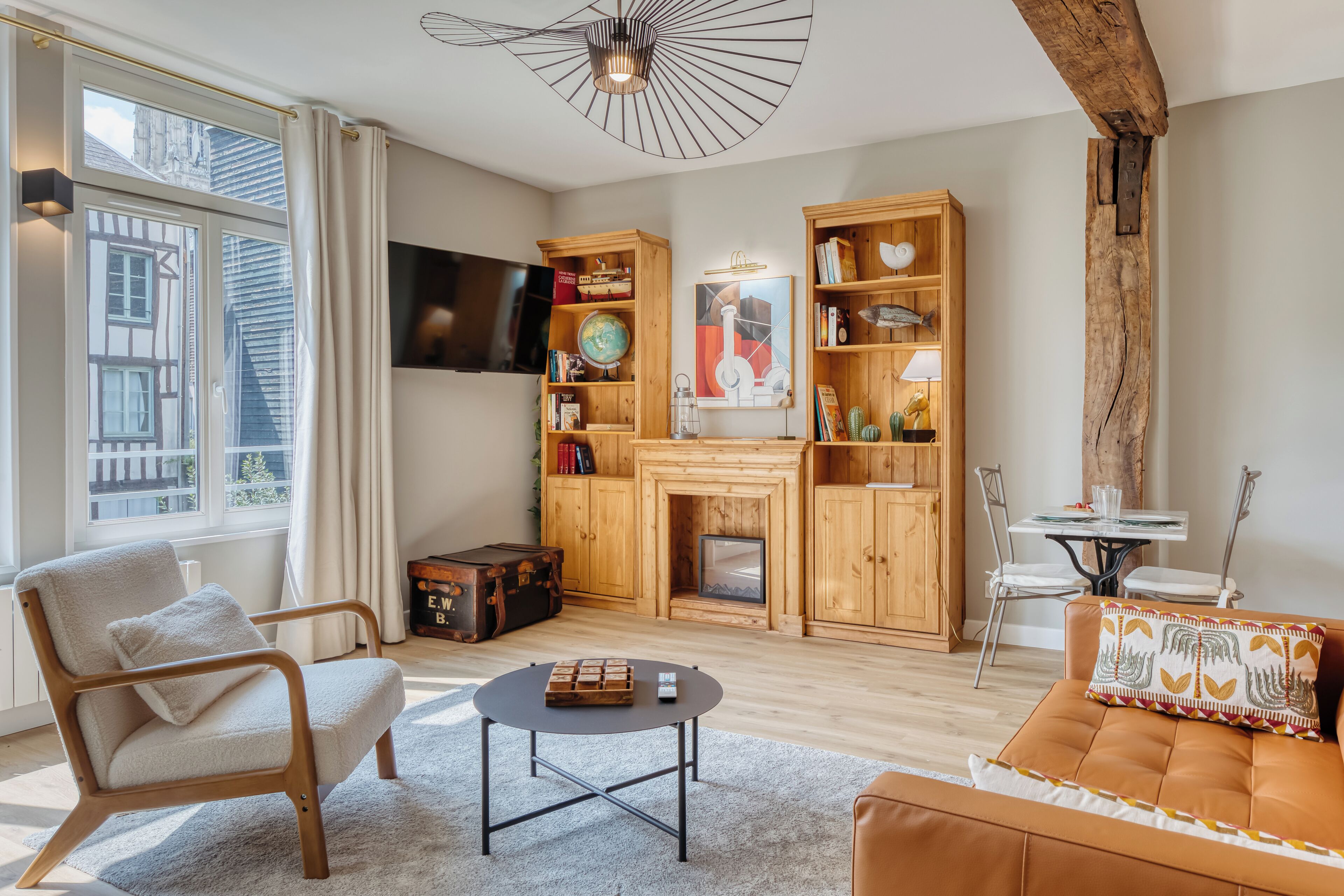 A living room with a fireplace, wooden bookshelves, a television, and a sofa.