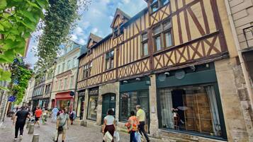 A cobblestone street lined with traditional half-timbered buildings, some with visible storefronts and signage.