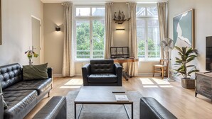 A modern living room with a leather sofa, a coffee table, a black armchair, and a desk with a computer. - La Venelle Saint-Nicolas (Rouen)