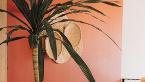 Een potplant, houten stoelen, een tafel en een wand met een geweven mand.
