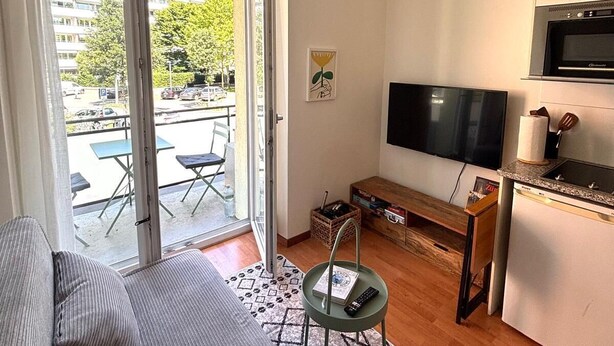 Un apartamento moderno con sofá, televisión, cocina y balcón amoblado.