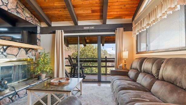 Una sala de estar acogedora con chimenea de piedra, un sofá de cuero y un comedor con mesa y sillas.