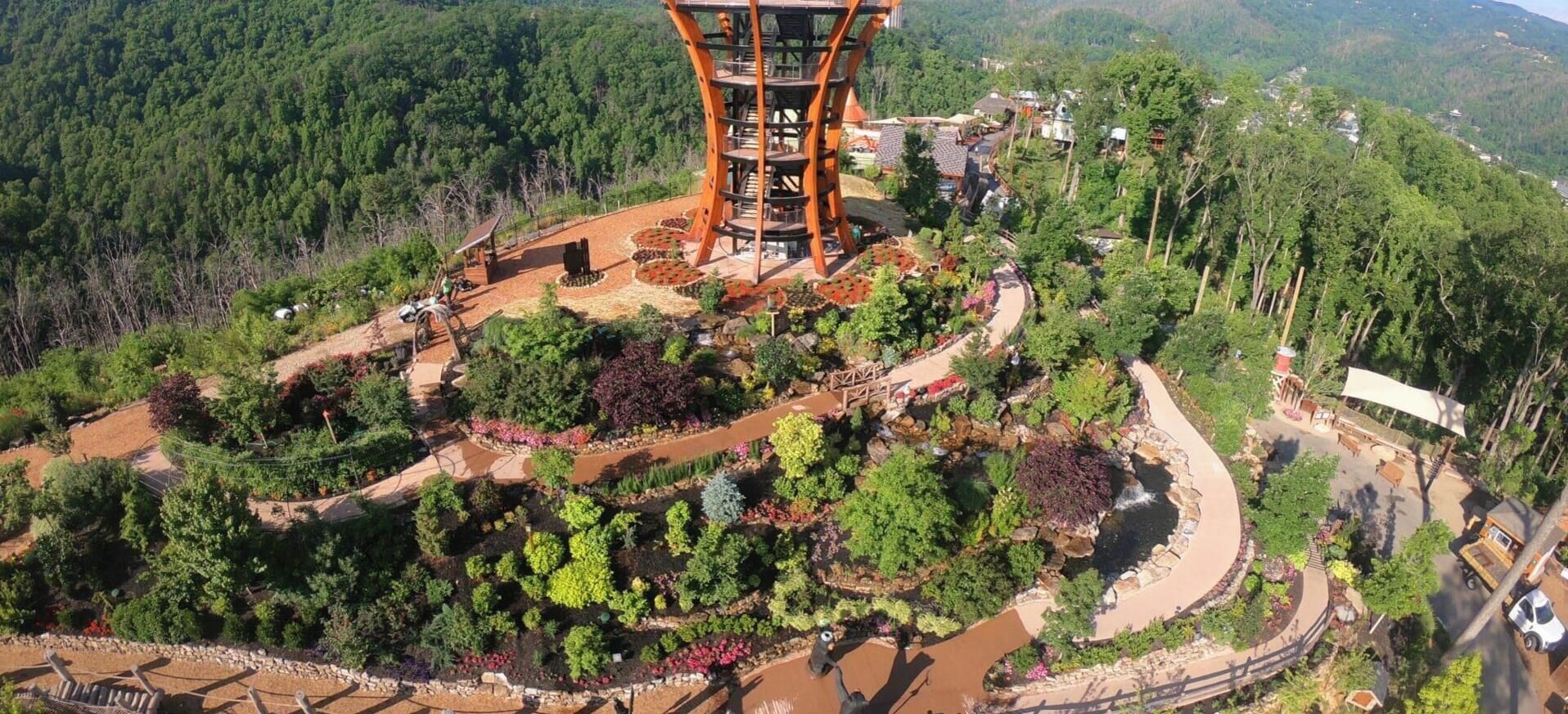 A multi-level structure with a spiral staircase, surrounded by terraced gardens and a small water feature.