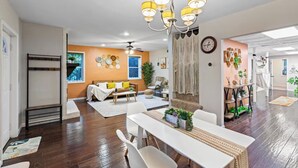 A spacious living area with a dining table, sofa, and a chandelier. - Suburban Buckhead Oasis - steps to beautiful park, playground, 5 min to midtown! (Atlanta)