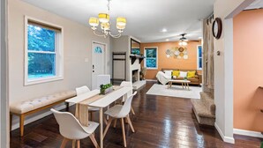 A modern living room with a sofa, dining table, chairs, and a chandelier. - Suburban Buckhead Oasis - steps to beautiful park, playground, 5 min to midtown! (Atlanta)