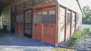 A stable with a metal gate, a covered entrance, and a small garden area. - Deluxe King One-Bedroom Cottage (Mobility Accessible) (Bronson)