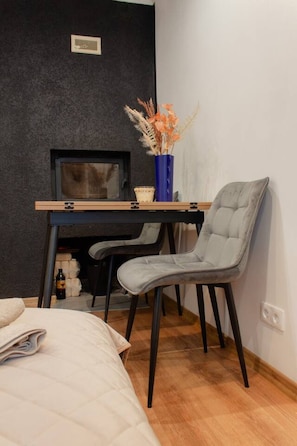 A bedroom with a bed, a desk with a computer, a chair, and a vase with flowers. - Cozy Studio at Pernavas 58 | Modern & Ground Floor (Rīga)