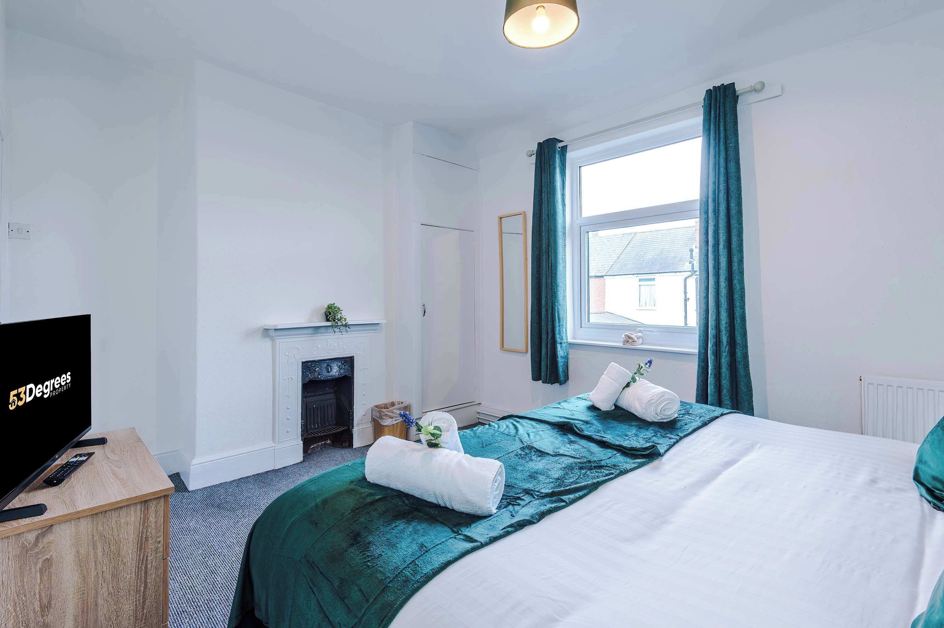 Une chambre d’hôtel avec un lit, une télévision, une cheminée et une fenêtre avec des rideaux.